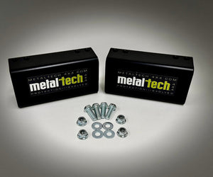 Two black Metal Tech rear bump stop drop blocks with bolts, nuts, and washers for FJ Cruiser and 4Runner long travel suspension.