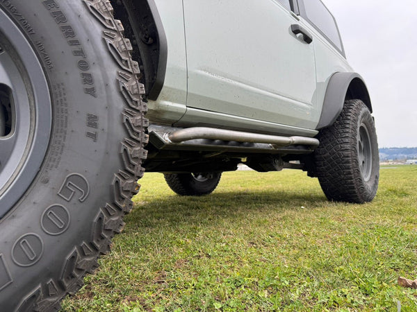 Close-up of raw metal Sidewinder RRR rock sliders installed on the driver side of a 2021 Ford Bronco 2-door.