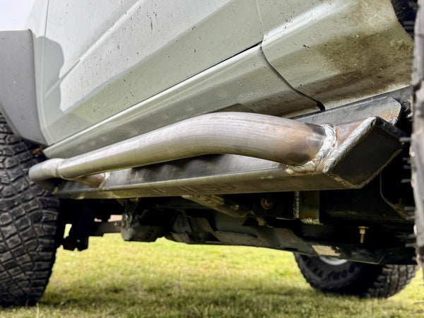 Close-up of raw metal Sidewinder RRR rock slider installed on 2021 Ford Bronco 2-door, showing weld details and tire tread.