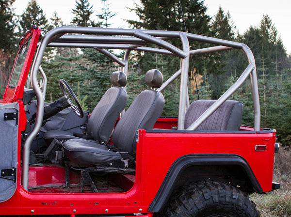 Side view of red FJ40 Land Cruiser with installed full-profile metal roll cage and black seats in outdoor setting.