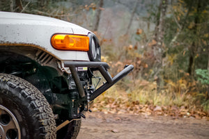 Close-up of Metal Tech front tube bumper installed on white FJ Cruiser with off-road tire and autumn background.