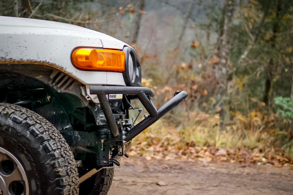 Close-up of Metal Tech front tube bumper installed on white FJ Cruiser with off-road tire and autumn background.