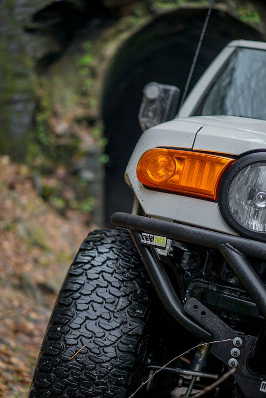 Close-up of Metal Tech front tube bumper installed on white FJ Cruiser with off-road tire and amber turn signal.