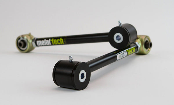 Close-up of two black Metal Tech rear upper and lower suspension links for FJ Cruiser and 4Runner with bushings and grease fittings.