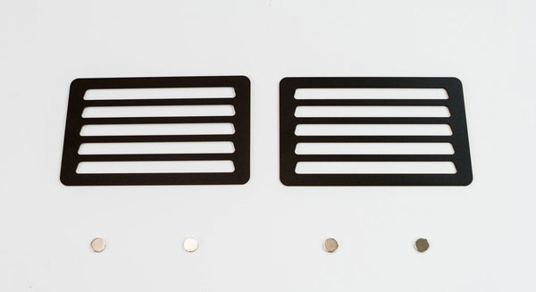 Pair of black metal winch hole covers with horizontal slots and four small round magnets on white background.