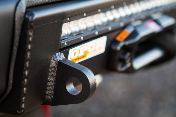 Close-up of black welded steel mounting bracket on 2016 Tacoma Stronghold winch bumper with LED light bar.