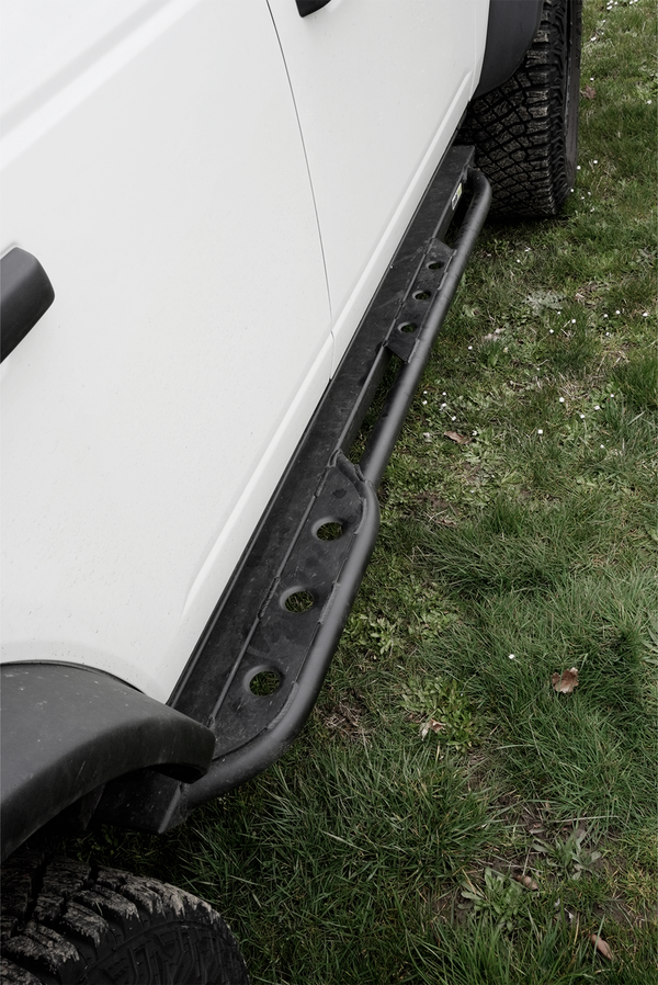 Close-up of black metal rock slider installed on the side of a white 2021 Ford Bronco 4-door.