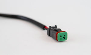 Close-up of black and green Toyota fog light harness connector for 2010 4Runner, Tundra, Tacoma on white background.