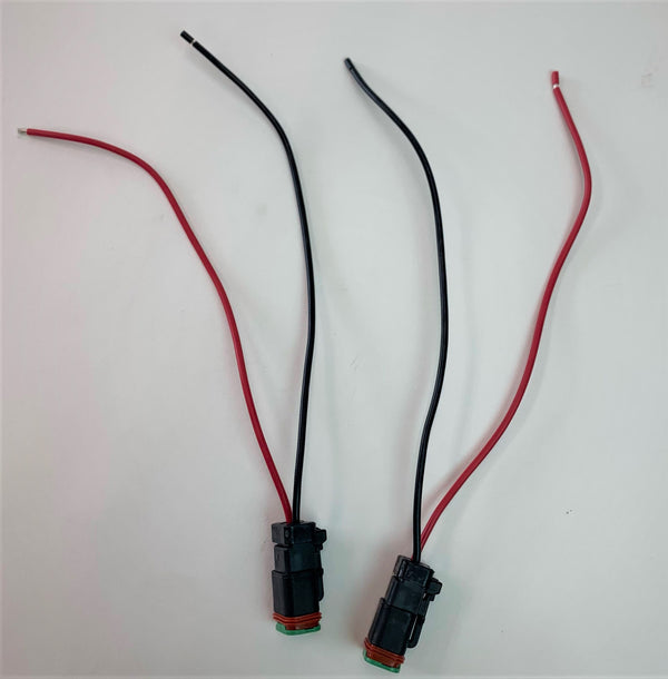 Pair of black and red Deutsch DT electrical plugs with bare wire ends on white background.