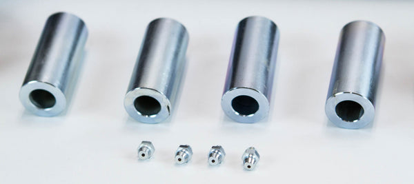 Four cylindrical metal spacers with four small grease fittings arranged below on a white surface.