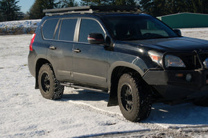 Black 2010 Lexus GX460 with Metal Tech 4x4 rock sliders installed on snowy terrain, side view.