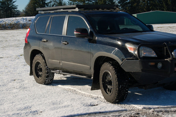 Black 2010 Lexus GX460 with Metal Tech 4x4 rock sliders installed on snowy terrain, side view.