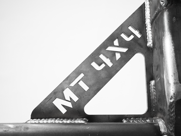 Close-up of welded metal bracket with "MT 4X4" cutout on Bronco 6G rear bumper swing arm system.