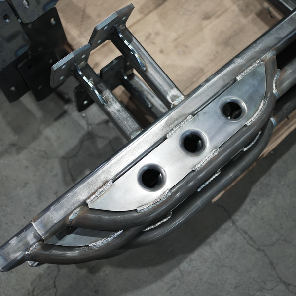 Close-up of raw metal rock slider with welded mounting brackets and circular cutouts for Lexus GX460 2010.