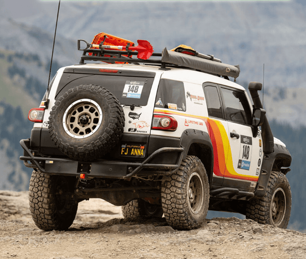 White FJ Cruiser with Metal Tech rear tube bumper and off-road gear on rugged terrain.