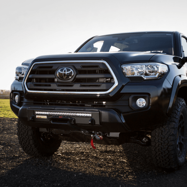 Front view of a black 2016 Toyota Tacoma with a Stronghold winch bumper and LED light bar installed.