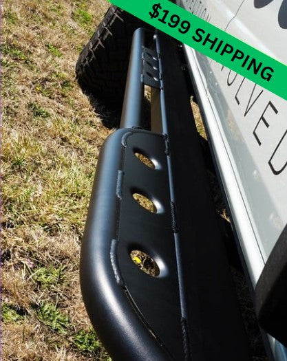 Close-up of black metal rock slider installed on 2021 Ford Bronco 4-door, showing welded mounting points and tubular design.