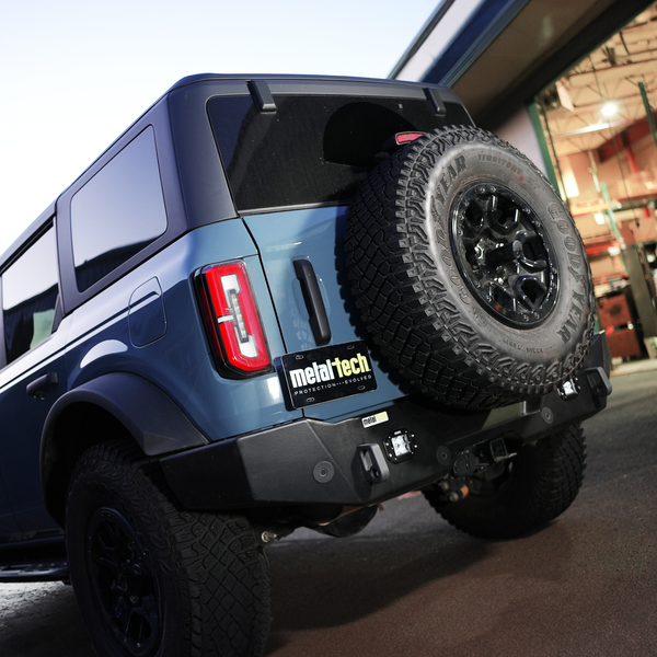 Rear view of blue Bronco 6G with Metal Tech 4x4 high rear bumper and mounted spare tire.