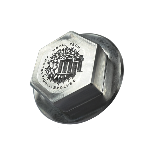 Close-up of a CNC-milled billet metal pivot cap with hexagonal top and engraved Metal Tech logo.