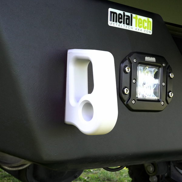 Close-up of white aluminum rear bumper pull point with Cerakote finish installed on black bumper next to LED light.